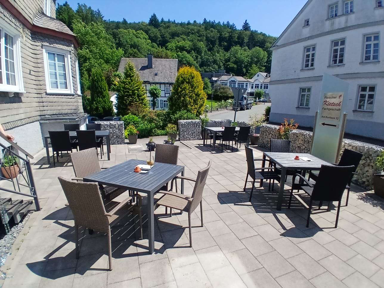 Sonnige Außenterrasse mit Tischen